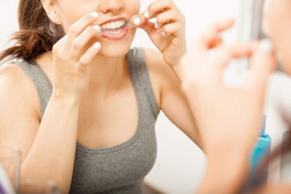 a cute brunette applying a whitening strip