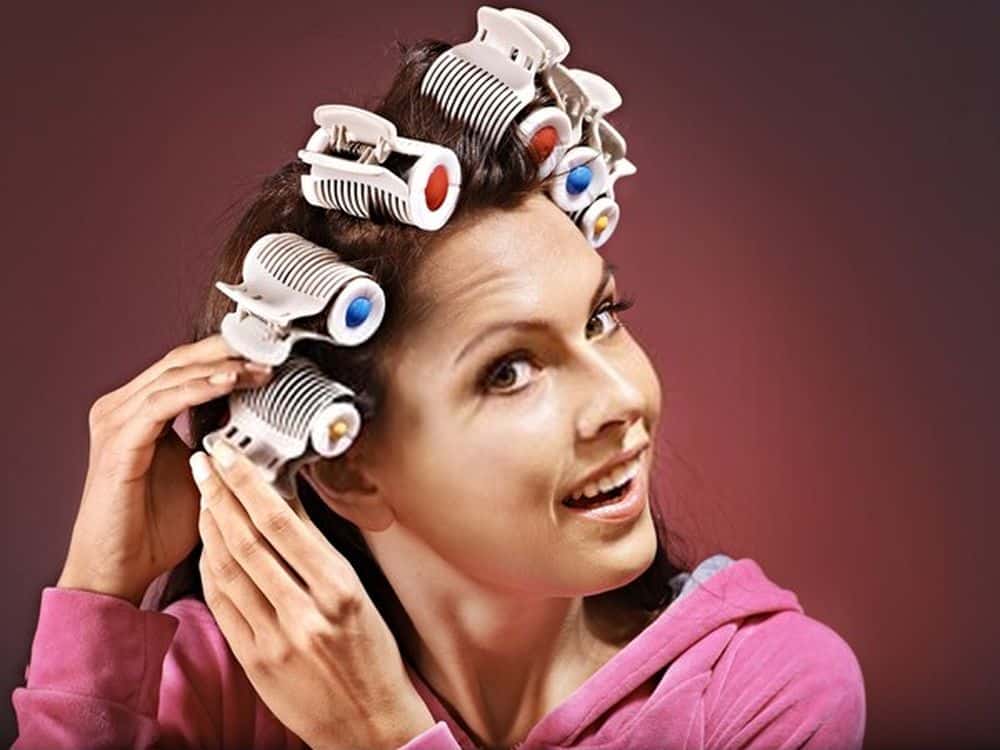 Happy woman wear hair curlers on head.