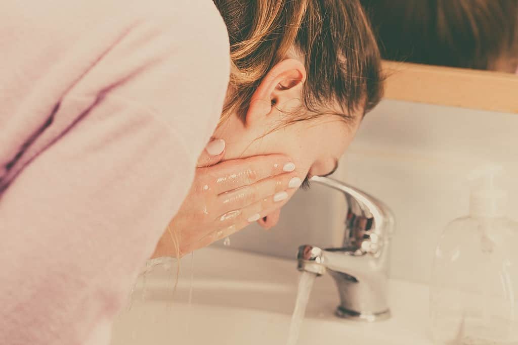 Woman washing face in bathroom