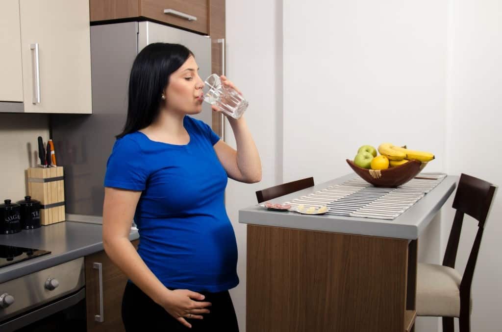 Young pregnant woman drinks water